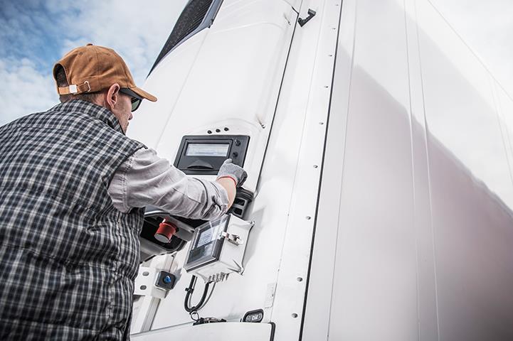 man adjusting temperature controls on refrigerated semi trailer truck