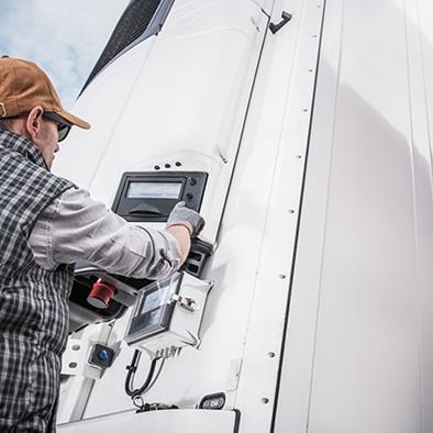 man adjusting temperature controls on refrigerated semi trailer truck
