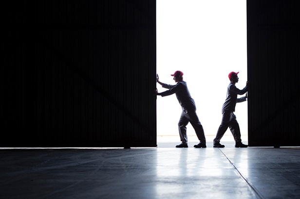 two workers opening up warehouse door