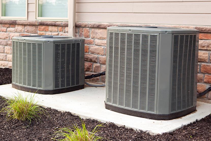 two air conditioner units along a building wall 