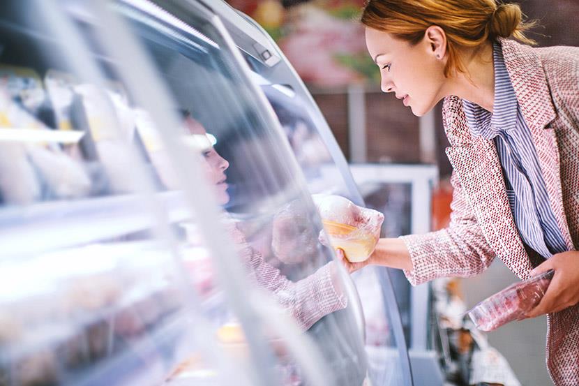 woman looking at wrapped meat in refrigerated display