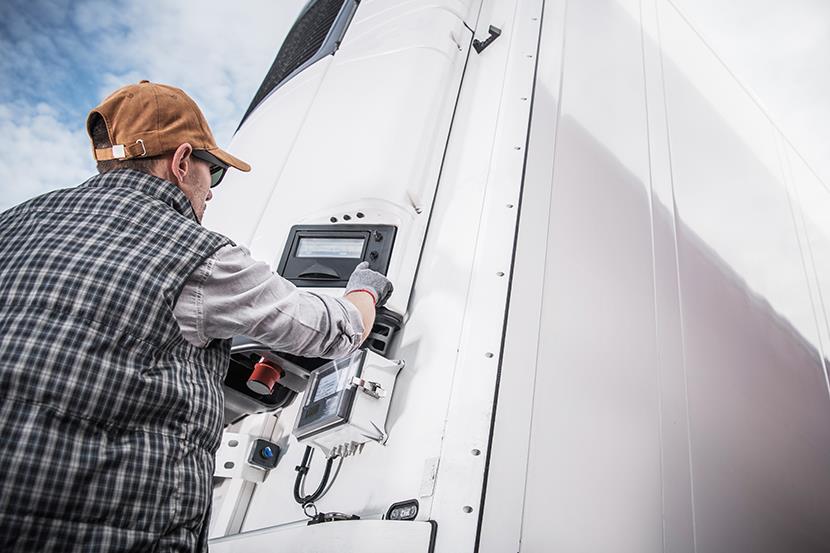 man adjusting temperature controls on refrigerated semi trailer truck