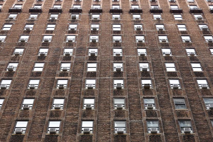 angled shot of apartment building windows with many ac units
